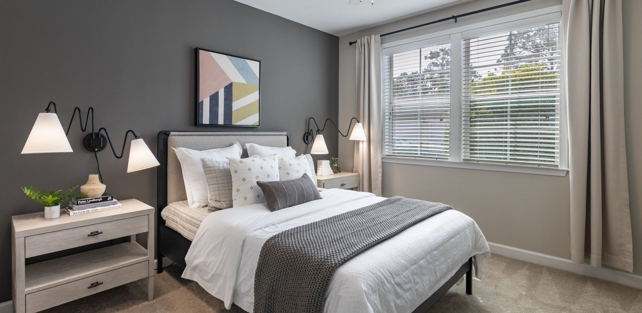 Comfortably appointed bedroom with modern geometric art above the bed at Hawthorne at Stillwater, embodying serene apartment living in Sneads Ferry, NC.